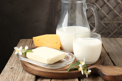 Photo of Different fresh dairy products and flowers on wooden table, closeup