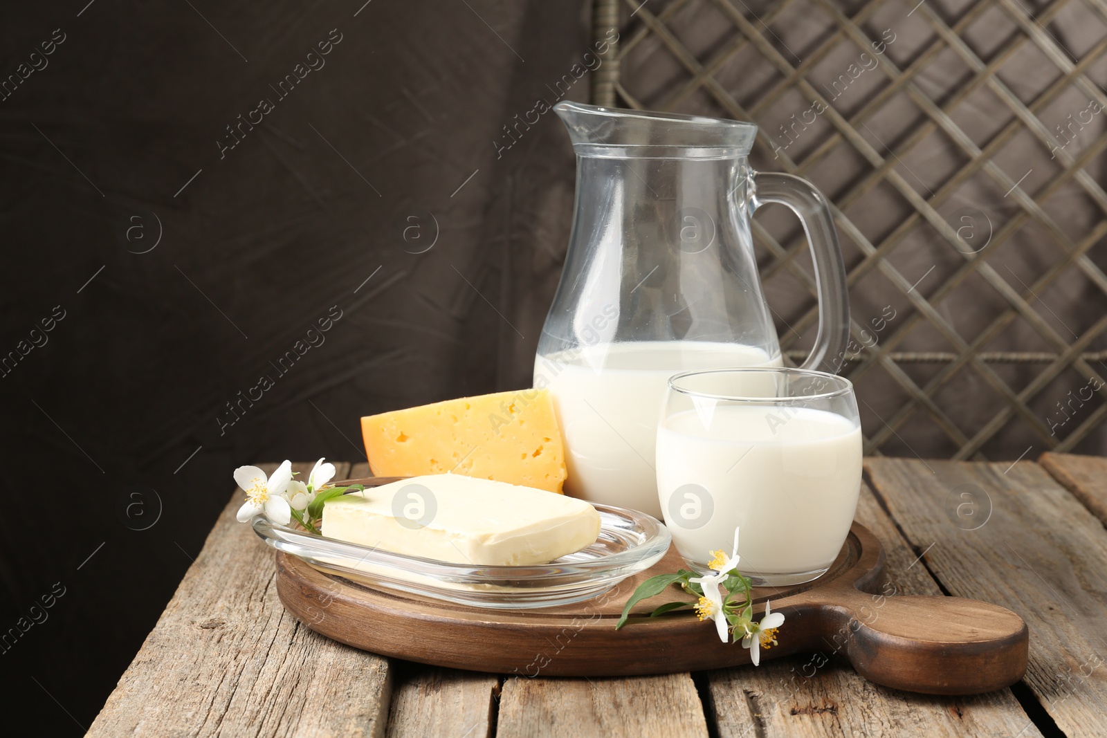 Photo of Different fresh dairy products and flowers on wooden table