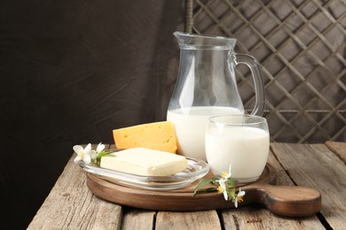 Photo of Different fresh dairy products and flowers on wooden table