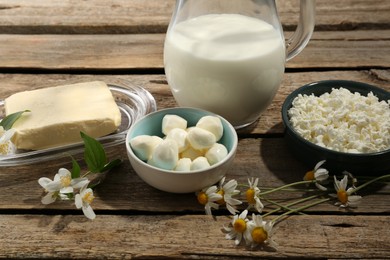 Photo of Different fresh dairy products and flowers on wooden table
