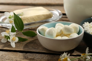 Photo of Different fresh dairy products and flowers on wooden table, closeup