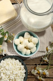 Photo of Different fresh dairy products and flowers on wooden table, flat lay