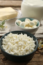 Photo of Different fresh dairy products and flowers on wooden table, closeup