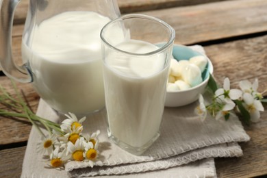 Photo of Fresh milk, mozzarella balls and flowers on wooden table, closeup. Dairy products