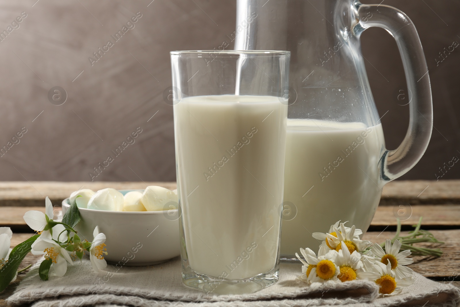 Photo of Fresh milk, mozzarella balls and flowers on wooden table, closeup. Dairy products