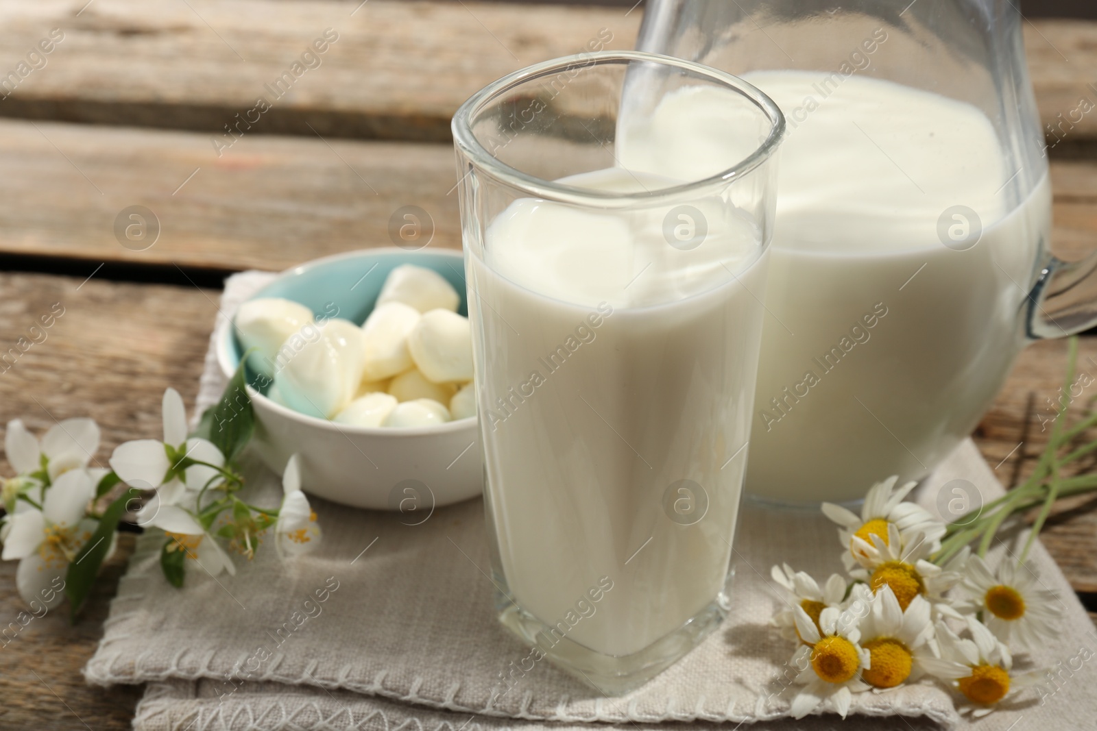 Fresh milk, mozzarella balls and flowers on wooden table, closeup. Dairy products Photo of Fresh milk, mozzarella balls and flowers on wooden table, closeup. Dairy products