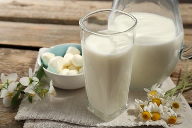 Photo of Fresh milk, mozzarella balls and flowers on wooden table, closeup. Dairy products