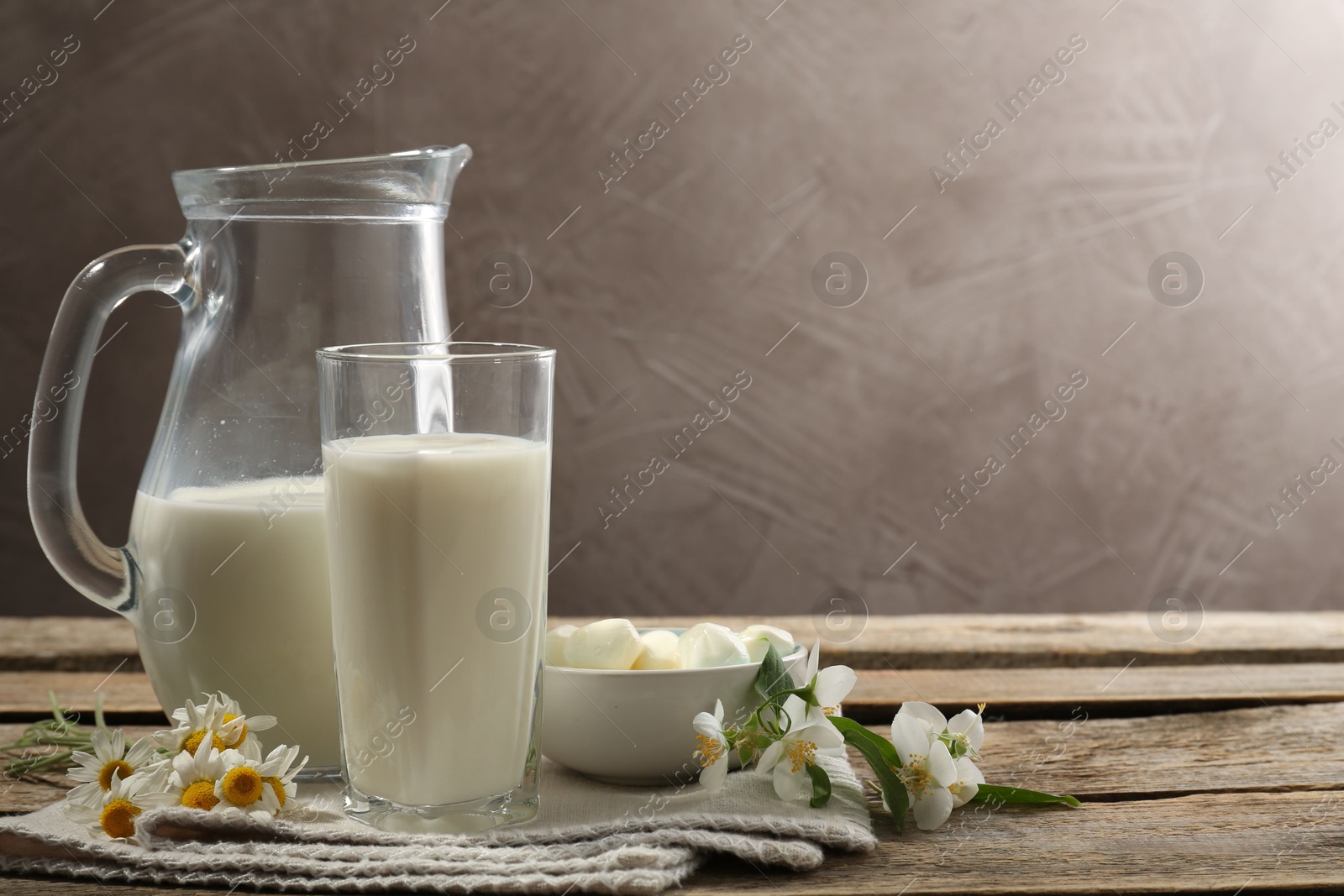 Fresh milk, mozzarella balls and flowers on wooden table, space for text. Dairy products Photo of Fresh milk, mozzarella balls and flowers on wooden table, space for text. Dairy products