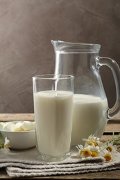Photo of Fresh milk, mozzarella balls and flowers on wooden table, closeup. Dairy products