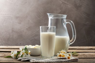 Photo of Fresh milk, mozzarella balls and flowers on wooden table. Dairy products