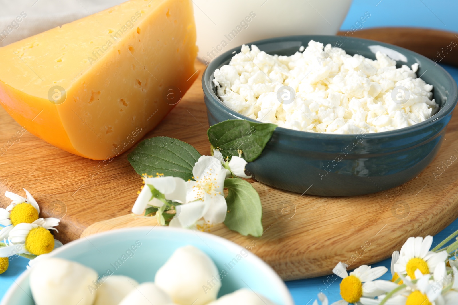 Photo of Different fresh dairy products and flowers on table, closeup