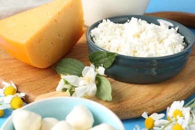 Photo of Different fresh dairy products and flowers on table, closeup