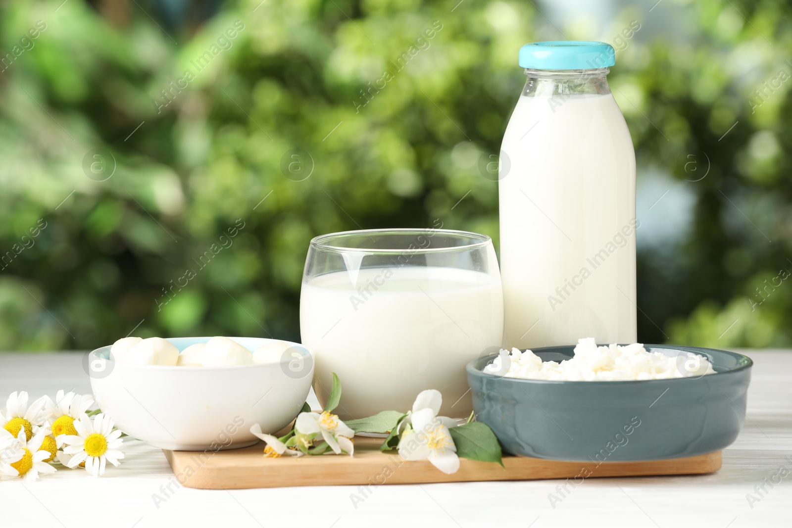 Different fresh dairy products and flowers on white wooden table outdoors Photo of Different fresh dairy products and flowers on white wooden table outdoors