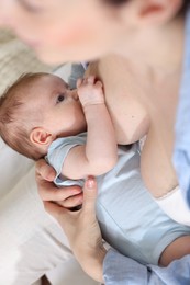 Photo of Mother breastfeeding her newborn baby indoors, above view
