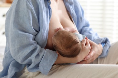 Photo of Mother breastfeeding her newborn baby indoors, closeup
