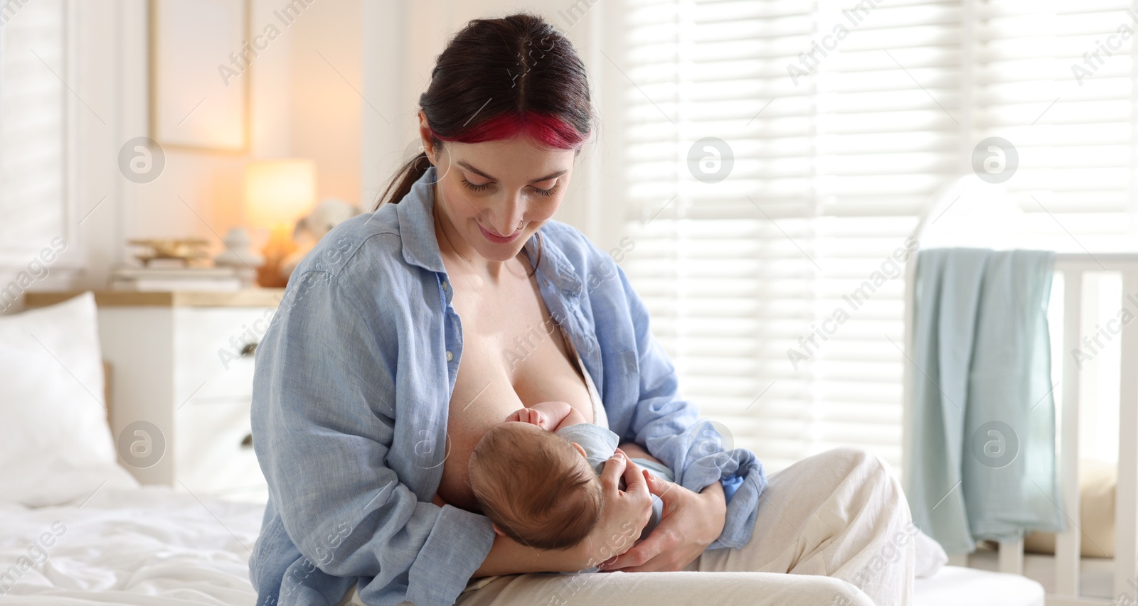 Mother breastfeeding her newborn baby on bed indoors Photo of Mother breastfeeding her newborn baby on bed indoors