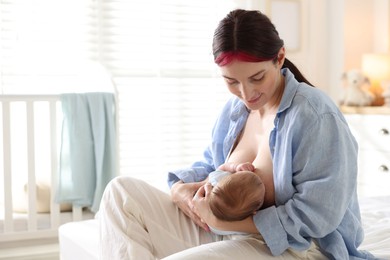 Photo of Mother breastfeeding her newborn baby on bed indoors