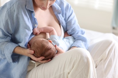 Photo of Mother breastfeeding her newborn baby indoors, closeup