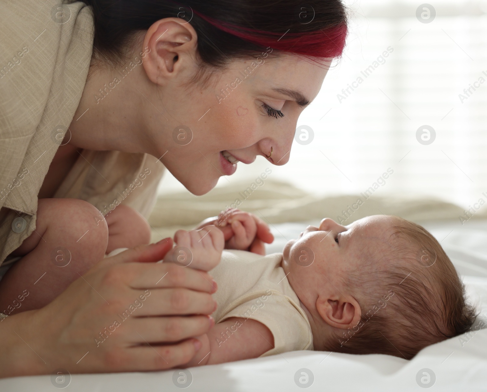 Mother with her newborn baby on bed indoors Photo of Mother with her newborn baby on bed indoors