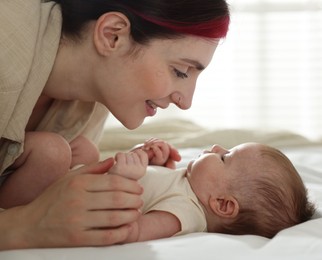 Photo of Mother with her newborn baby on bed indoors