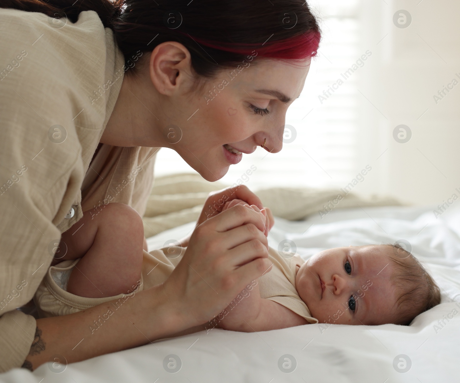 Mother with her newborn baby on bed indoors Photo of Mother with her newborn baby on bed indoors