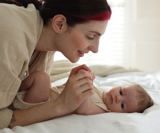 Photo of Mother with her newborn baby on bed indoors