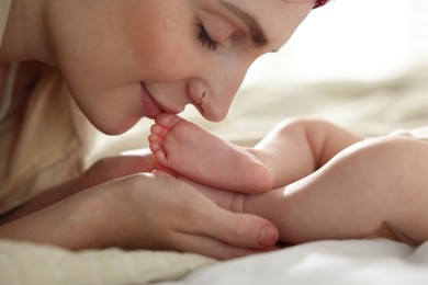 Photo of Mother with her newborn baby on bed indoors, closeup