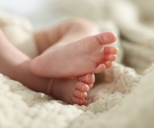 Photo of Cute newborn baby lying on bed indoors, closeup