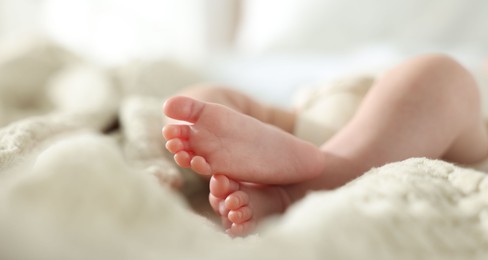 Photo of Cute newborn baby lying on bed indoors, closeup