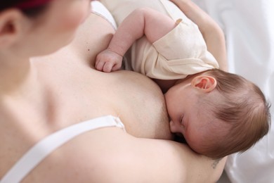 Photo of Mother breastfeeding her newborn baby indoors, above view