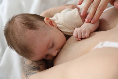 Photo of Mother breastfeeding her newborn baby indoors, above view