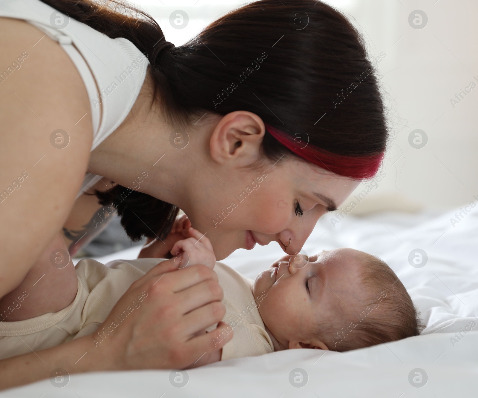 Mother with her newborn baby on bed indoors Photo of Mother with her newborn baby on bed indoors