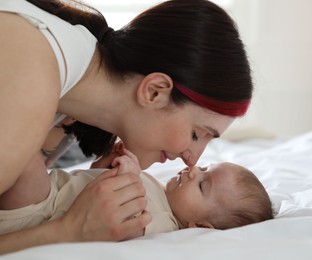 Photo of Mother with her newborn baby on bed indoors