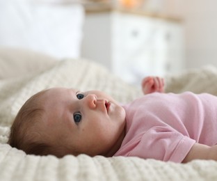 Photo of Cute newborn baby lying on bed indoors