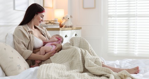 Photo of Mother with her newborn baby on bed indoors