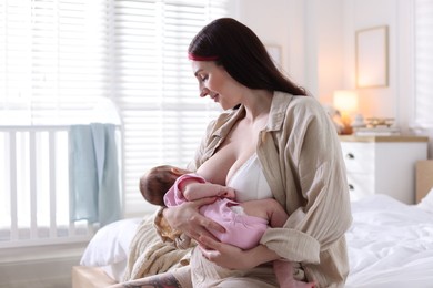 Photo of Mother breastfeeding her newborn baby on bed indoors
