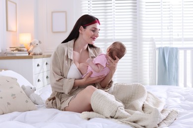 Photo of Mother with her newborn baby on bed indoors