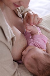 Photo of Mother breastfeeding her newborn baby indoors, closeup