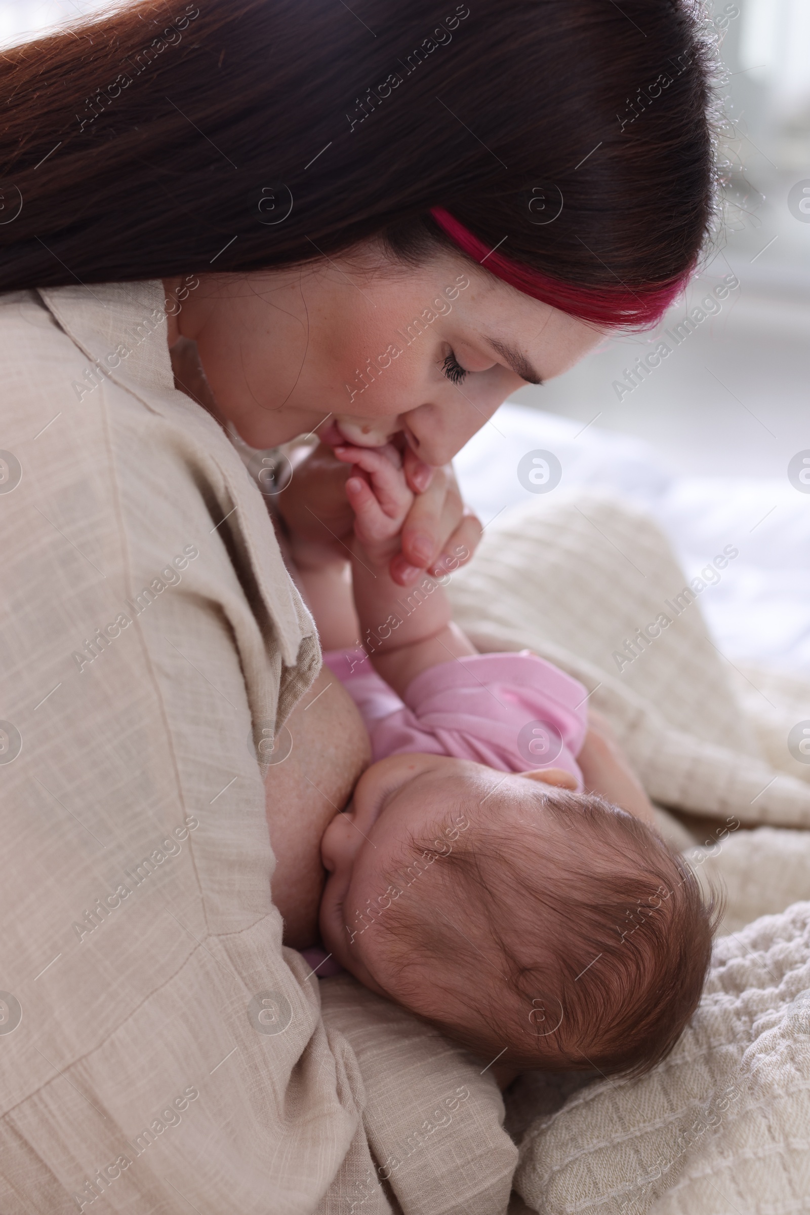 Mother breastfeeding her newborn baby on bed indoors Photo of Mother breastfeeding her newborn baby on bed indoors