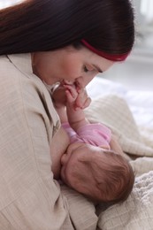 Photo of Mother breastfeeding her newborn baby on bed indoors