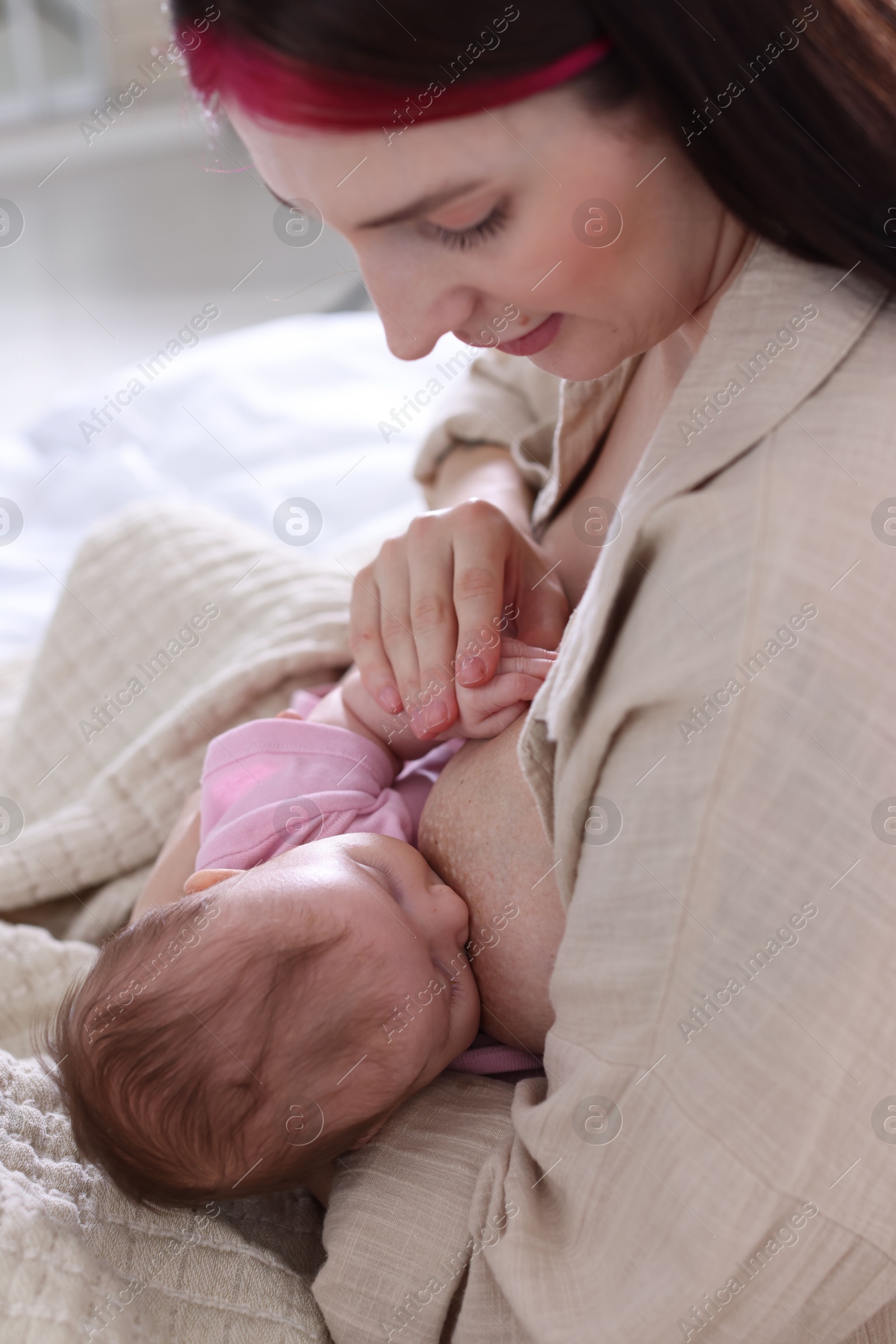 Mother breastfeeding her newborn baby on bed indoors Photo of Mother breastfeeding her newborn baby on bed indoors