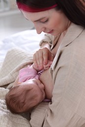 Photo of Mother breastfeeding her newborn baby on bed indoors