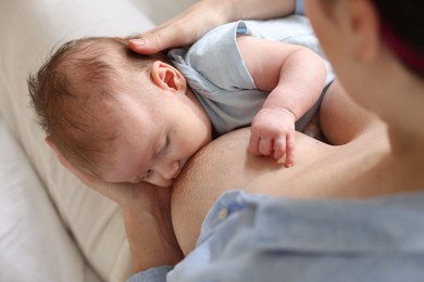 Photo of Mother breastfeeding her newborn baby indoors, above view