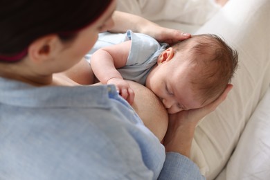 Photo of Mother breastfeeding her newborn baby indoors, above view
