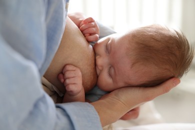 Photo of Mother breastfeeding her newborn baby indoors, closeup