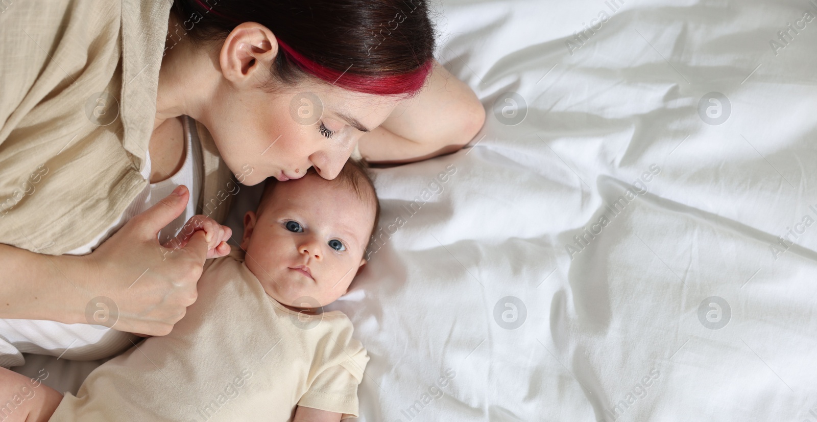 Mother with her newborn baby on bed indoors, top view. Space for text Photo of Mother with her newborn baby on bed indoors, top view. Space for text