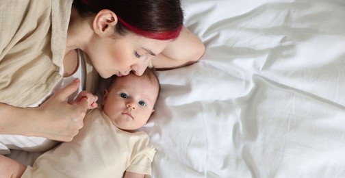 Photo of Mother with her newborn baby on bed indoors, top view. Space for text