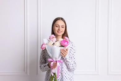 Photo of Woman with beautiful bouquet of peonies near white wall indoors