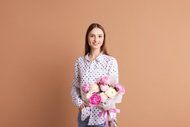 Photo of Woman with beautiful bouquet of peonies on dark beige background