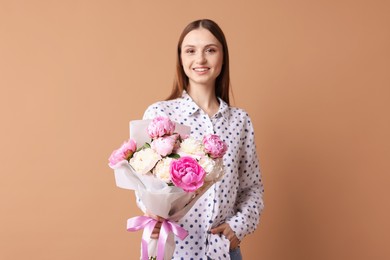 Photo of Woman with beautiful bouquet of peonies on dark beige background